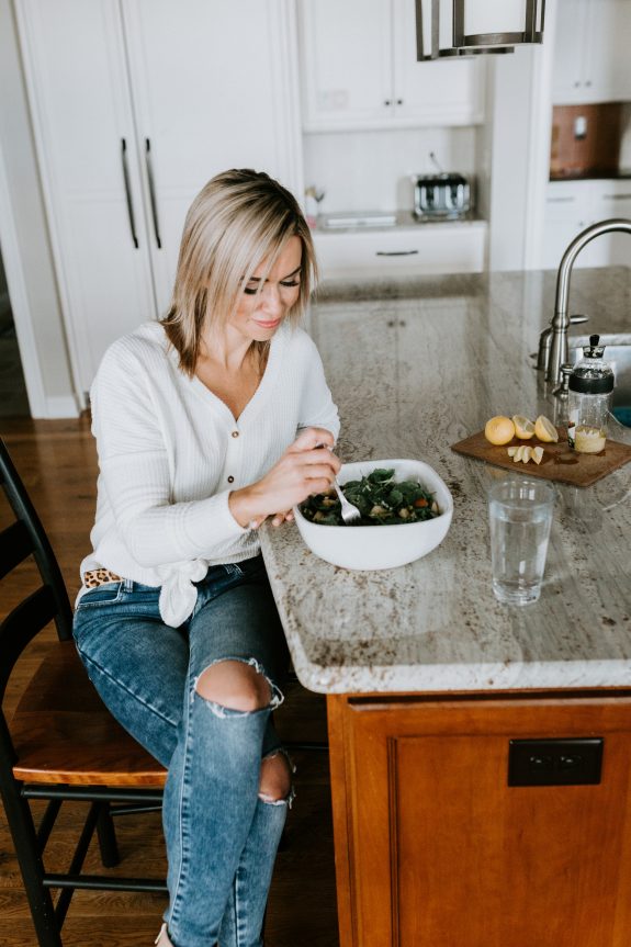 Kelly Ruth eating a homemade salad while sitting at her kitchen counter. 